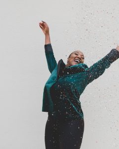 woman in green jacket raising her hands