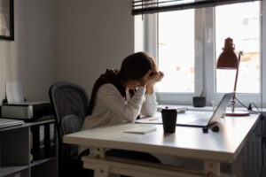 Women at an office desk with her head in her hands