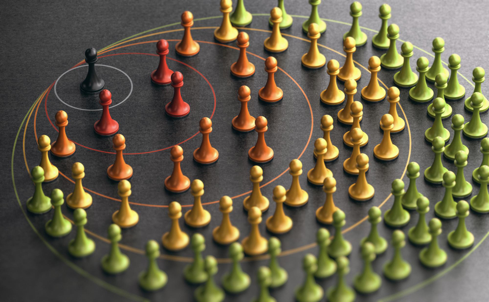 Many colorful pawns on a black surface with concentric circles, the pawns are arranged in groups by color, the background is plain